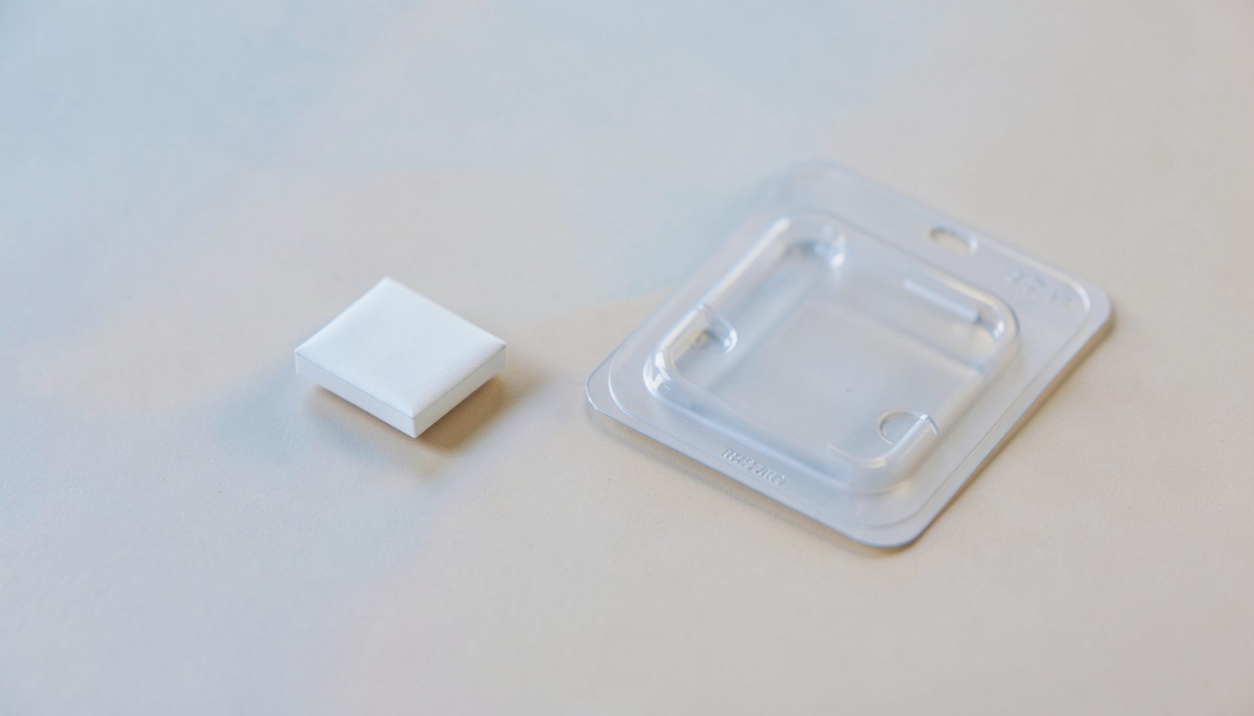 A small discreet package and a blister pack on a clean neutral surface, with soft blue and warm beige tones, conveying privacy and accessibility.